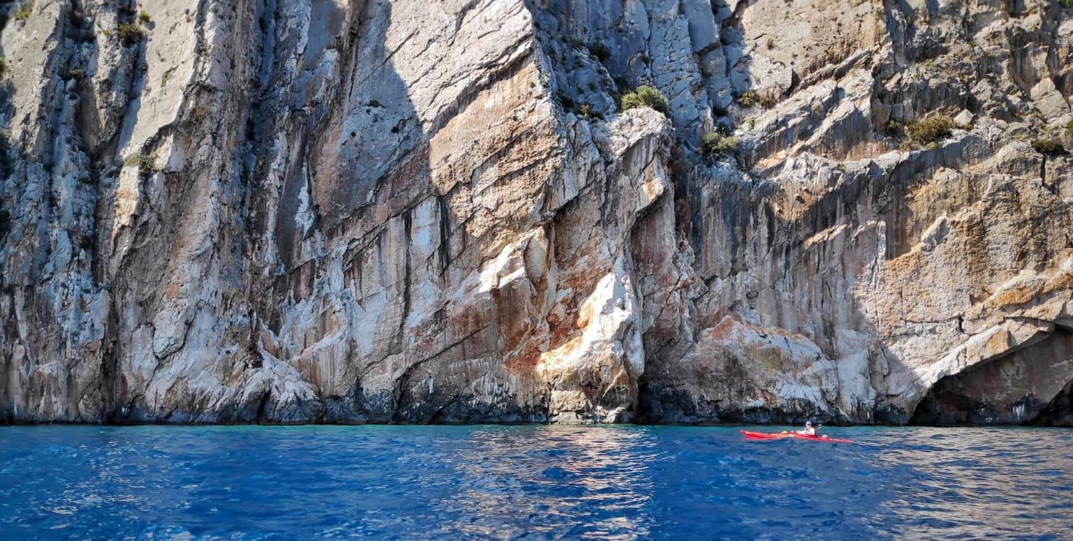 Sea kayaking under steep cliffs of Hvar island - AndAdventure